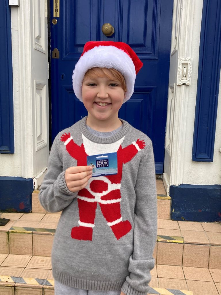 Harry Bowley wearing Christmas jumper and holding gift card he won.